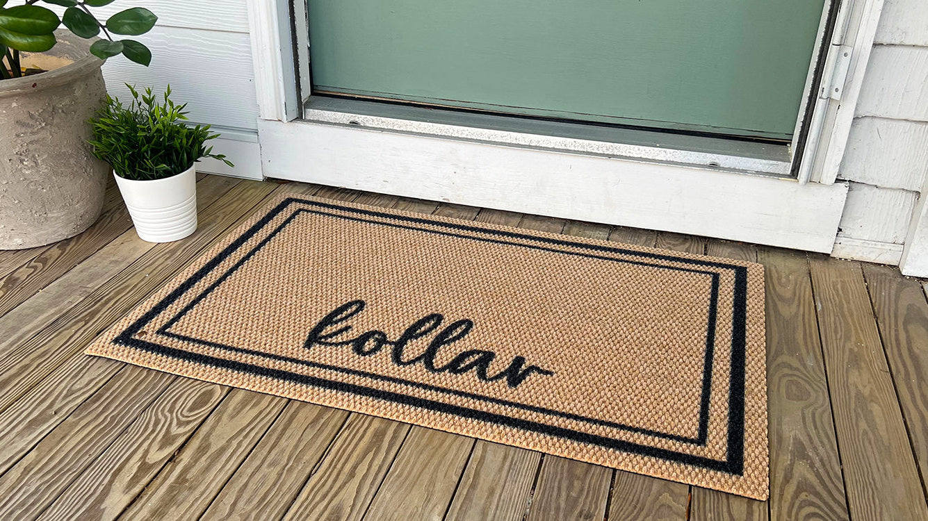 Neighburly Around the Block personalized doormat featuring a family last name in a black and brown color scheme and is placed at a green front door in order clean the bottom of shoes and boots before they go indoors.