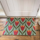 Sage and berry colored Buttercups single door doormat in front of a shut door.