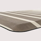 Corner of Happy Feet anti-fatigue mat with dark beige/light brown stripes with a canvas-like texture.