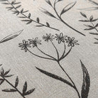 beige canvas-like textured surface with black/brown botanical design.