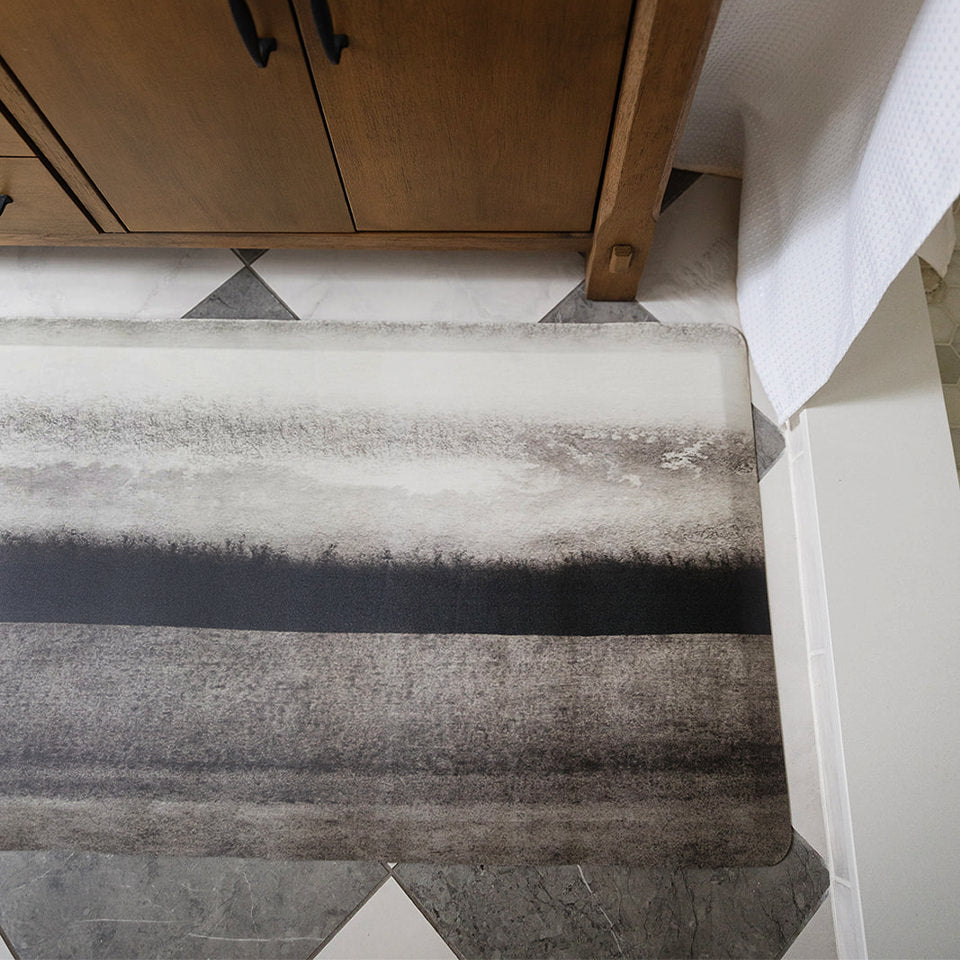 Happy Feet's Moody Hues anti-fatigue bath mat depicting field scene in white, black, and greys.