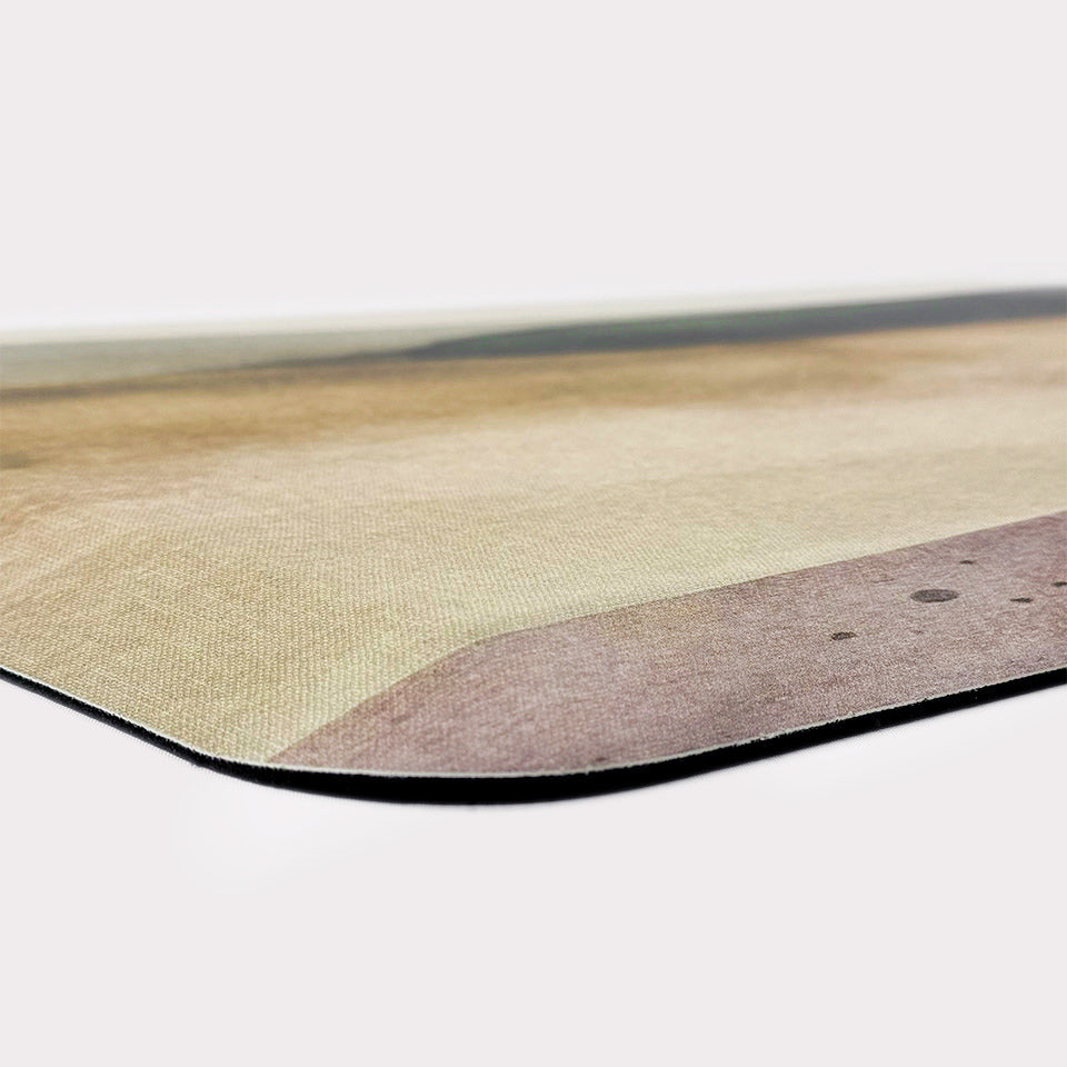 Corner of Happy Feet anti-fatigue foam cushion mat with watercolor landscape printed on a canvas-like texture.