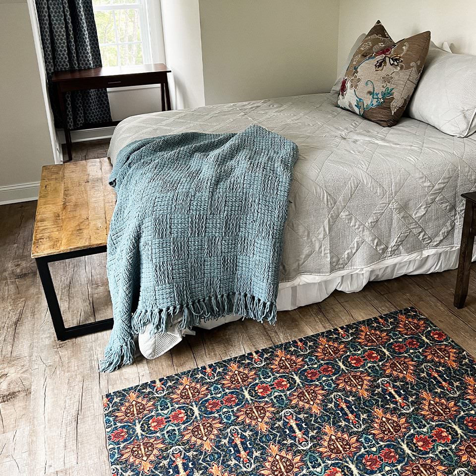 Low-profile Un-Rug Persian design mat in large placed next to a bed for comfort with it's soft surface and rubber backed construction.