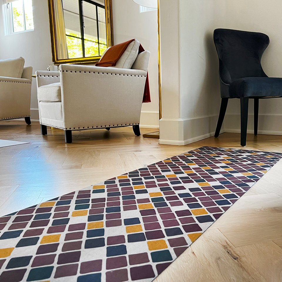 Beautiful Un-Rug in the Retro Squares design is covered in tiny squares in multiple colors, dark red, yellow, dark brown, and neutral beige while being used as a hallway runner mat.
