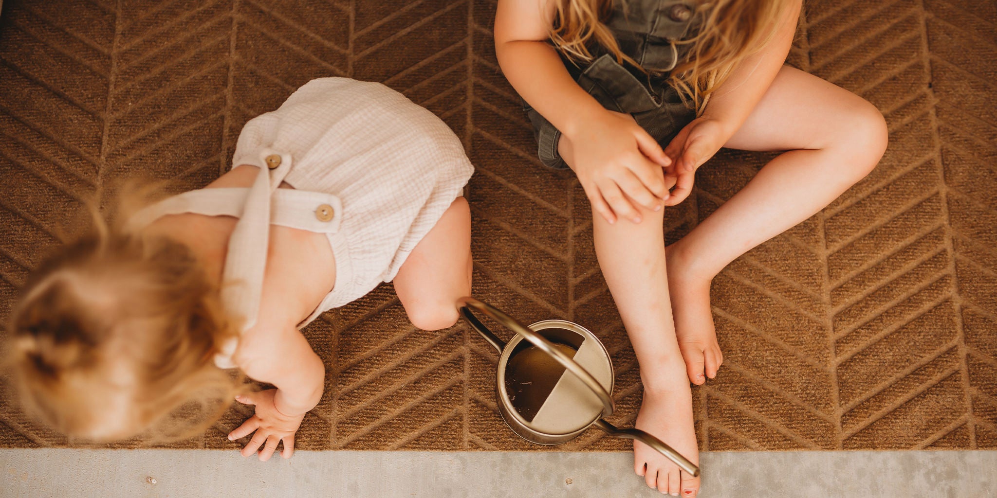 WaterHog Luxe In Vein double doormat with two kids playing on the wheat colored mat.