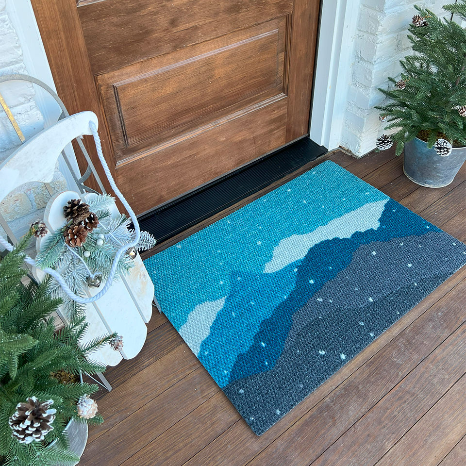 Holiday decorated front porch with beautiful wintery landscape welcome mat; featuring snowy mountains in shades of blues, greens, and white.