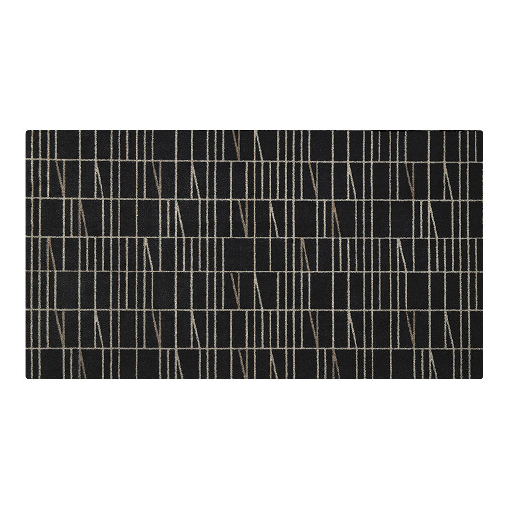 Maxcent Biblioteca medium mat in Charcoal – a long, low-profile rug featuring a geometric grid and angled light grey line pattern across a dark background. Designed with a soft carpeted surface and non-slip rubber backing for secure placement in hallways or entryways.