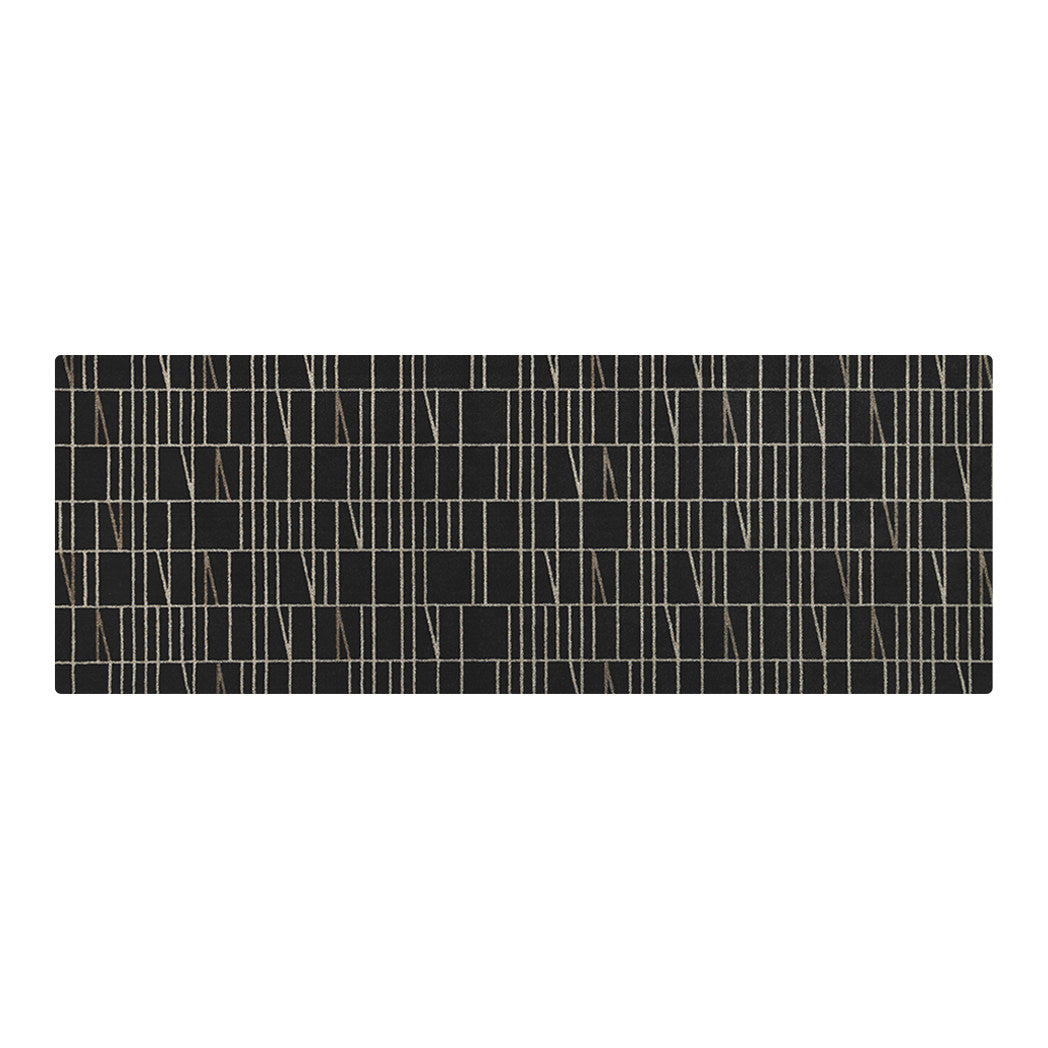 Maxcent Biblioteca runner mat in Charcoal – a long area rug featuring a deep black background with light tan and gray linear accents in a modern grid pattern. The carpeted surface adds softness underfoot, and the non-slip rubber backing helps keep it firmly in place on hard floors.
