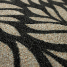 Close-up of the Maxcent Botanica mat in Space Grey, showing the textured carpeted surface with a bold black leaf pattern over a soft gray base. The detailed weave provides a comfortable feel underfoot and enhances the visual depth of the design.