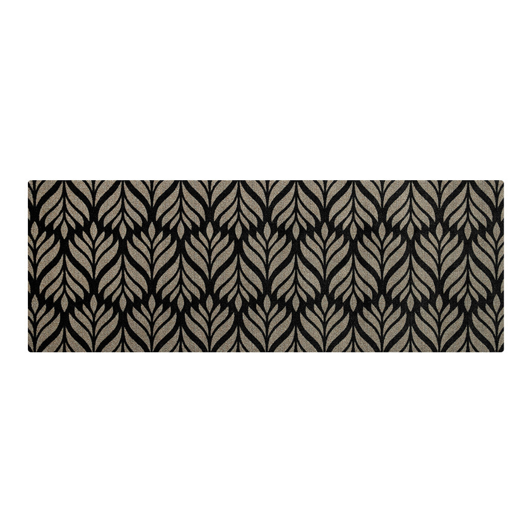 Maxcent Botanica runner mat in Space Grey – features a repeating gray leaf pattern set against a black background in a long, rectangular format. Ideal for hallways or kitchens, the mat combines a soft carpeted surface with a non-slip rubber backing for comfort and stability on hard floors.
