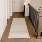 Maxcent Classic Stripe runner in a hallway, styled with narrow beige and grey stripes. The rug extends neatly down the wood floor corridor, adding texture and warmth while offering a non-slip surface in a high-traffic area.