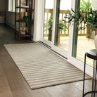 "Maxcent Classic Stripe runner placed at a sliding glass door entryway, featuring alternating beige and grey stripes. The long shape fits perfectly along the doorway, helping catch dirt and moisture while complementing natural light and wood flooring.