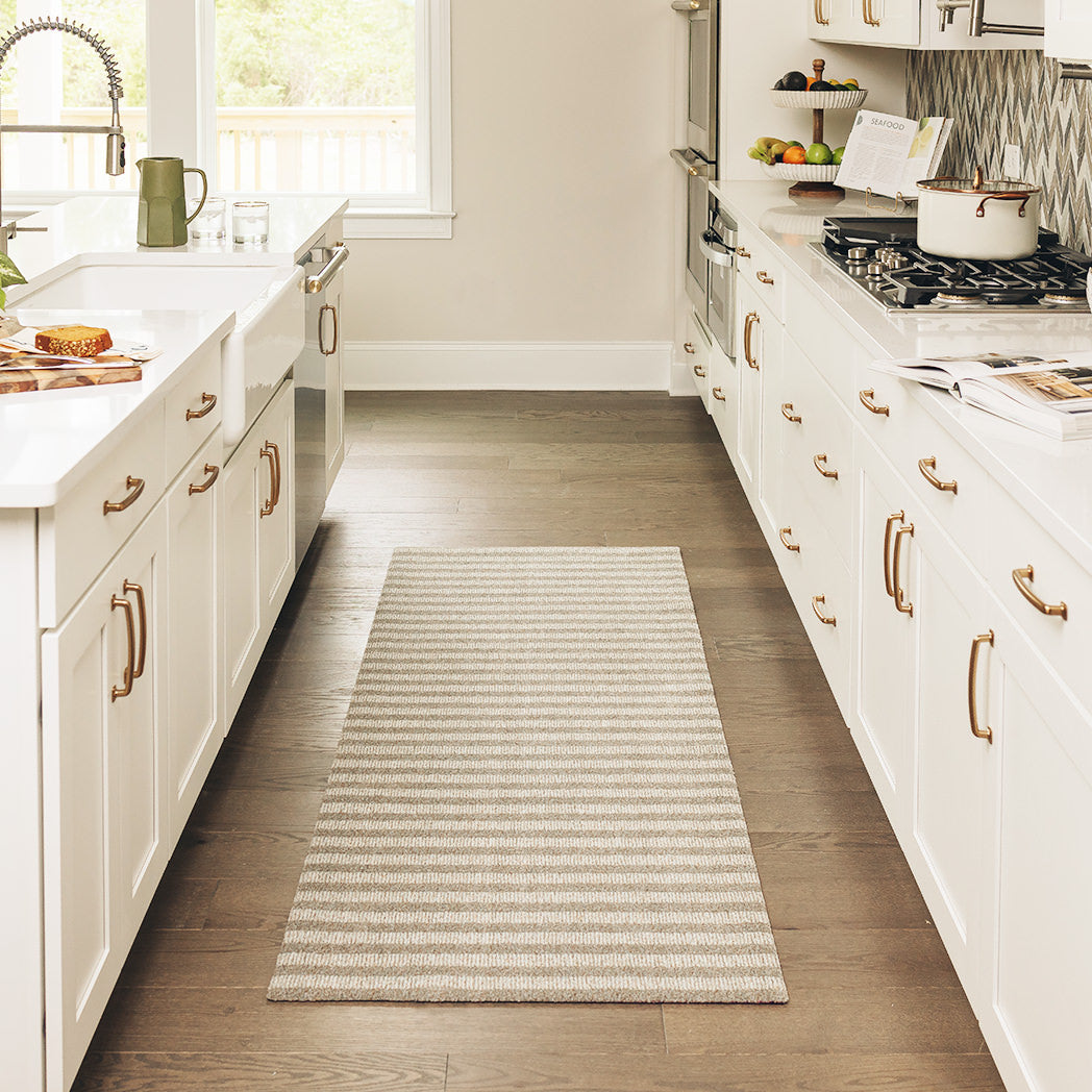 Maxcent Classic Stripe runner mat in a modern kitchen – features alternating vertical stripes in light beige and grey tones, creating a clean, tailored look. The extended size fits perfectly along galley-style cabinetry, with a soft carpeted surface and non-slip rubber backing for stability and comfort.