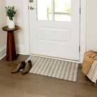 Maxcent Classic Stripe mat in a small size placed at a front door entryway. The mat’s soft beige and grey striped pattern complements the light wood flooring, offering a clean, neutral accent while helping catch dirt and moisture from shoes.