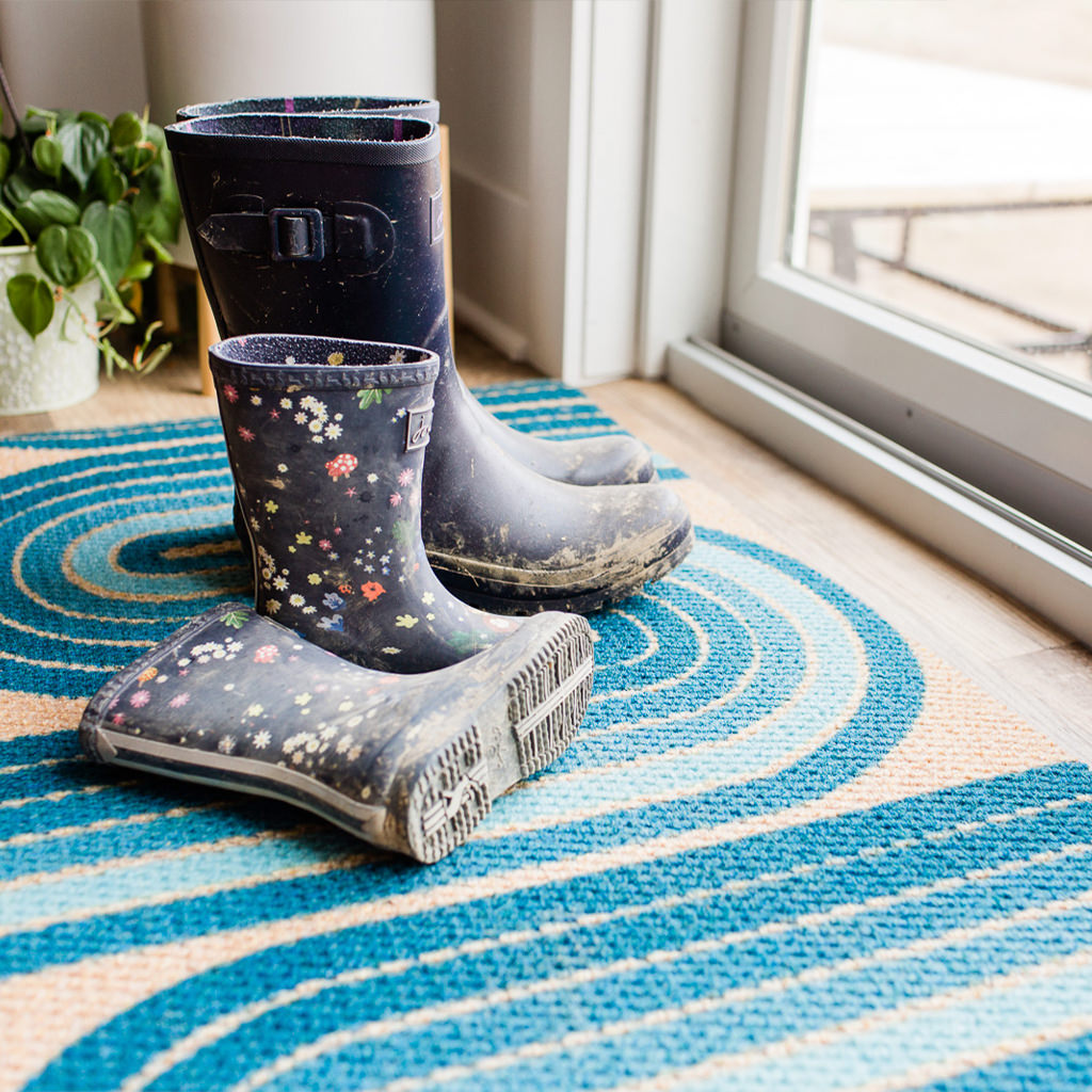 Two pairs of dirty boots on top of a Retro Vibe double doormat