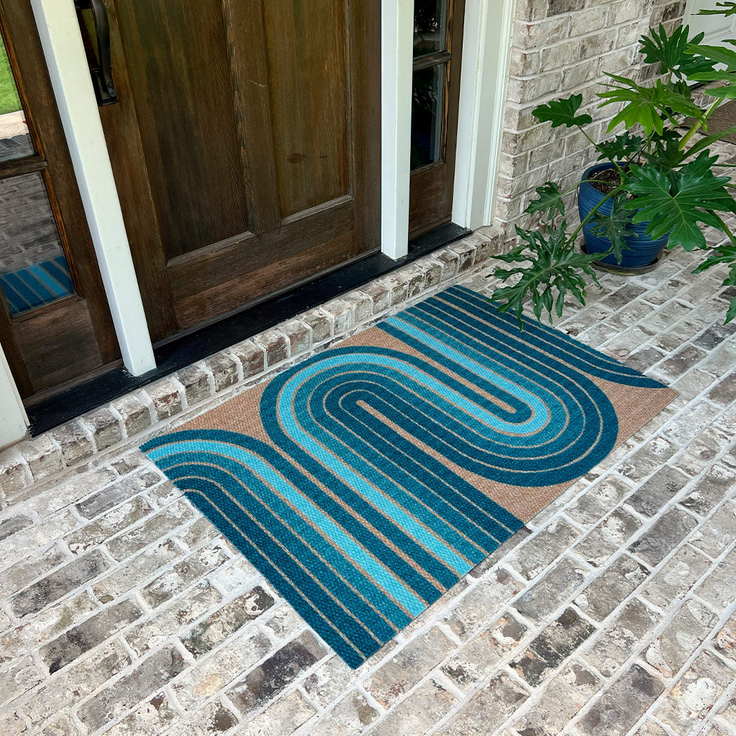 Decorative doormat with wavy blue pattern on a stone patio