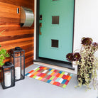 Neighburly Colorful Tulips door mat in front of a mid-century modern styled home blending the colors of the doormat.