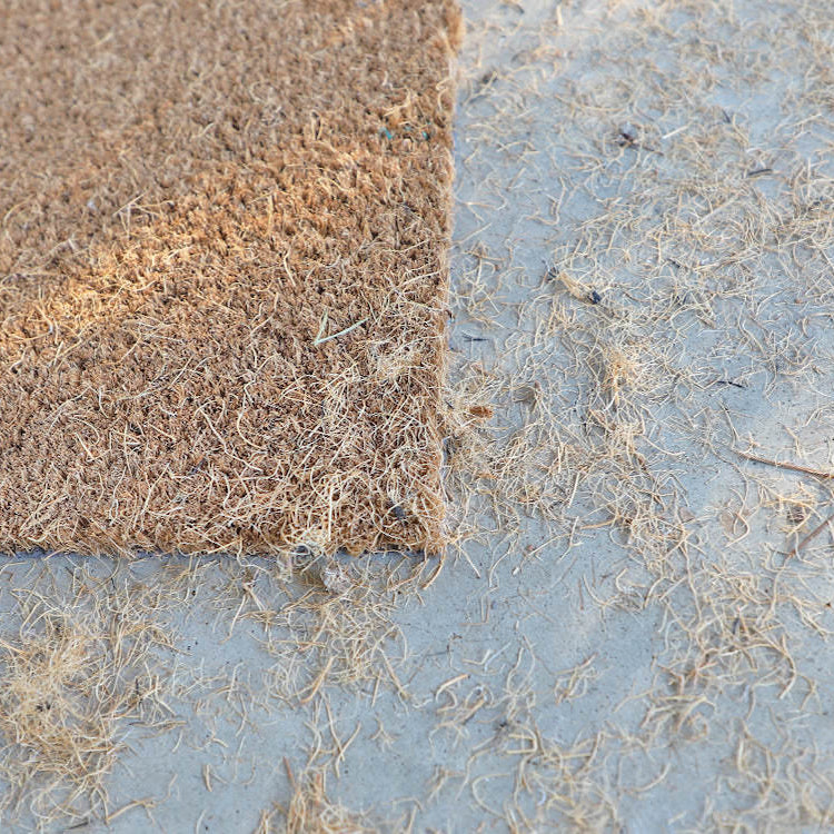 Close up picture of a coco mat that has shed it's fibers that will need to be cleaned up.