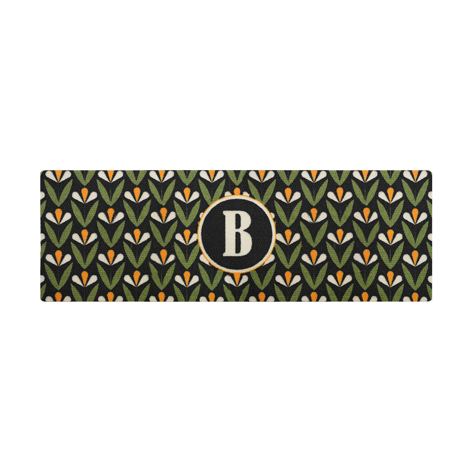 Spring Blooms double door monogrammed doormat in green, yellow and black shown on a covered porch by the front door.
