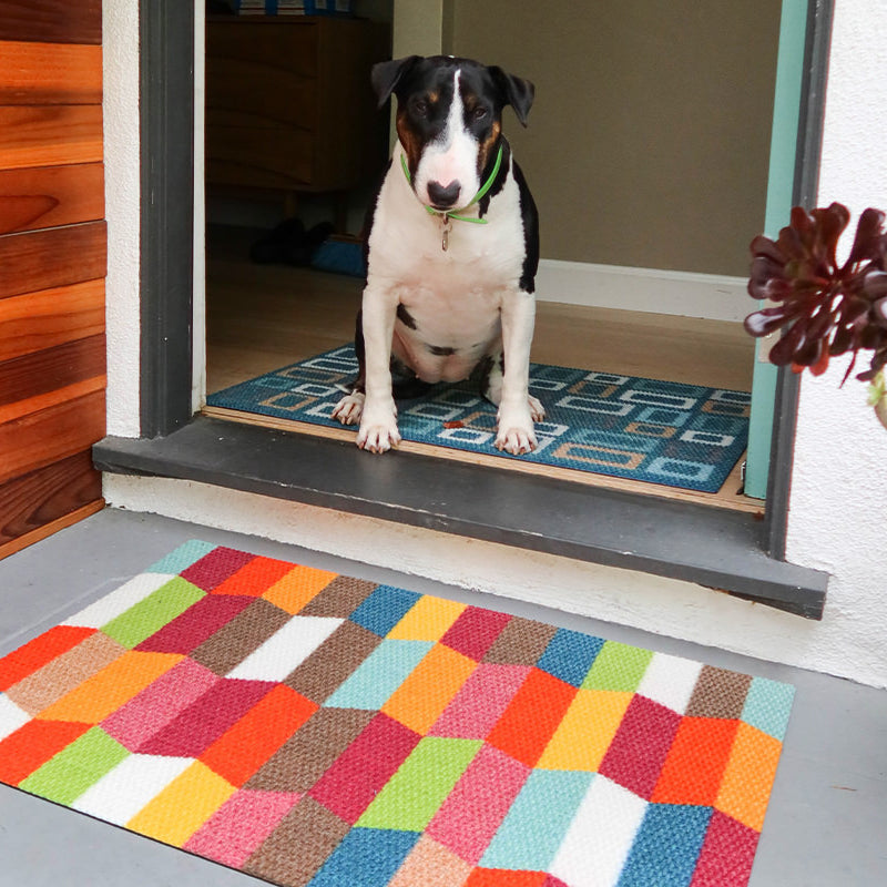 Neighburly Colorful Tulips low-profile entrance mat with a geometric design of bright reds, browns, blues, greens, yellows, and oranges.