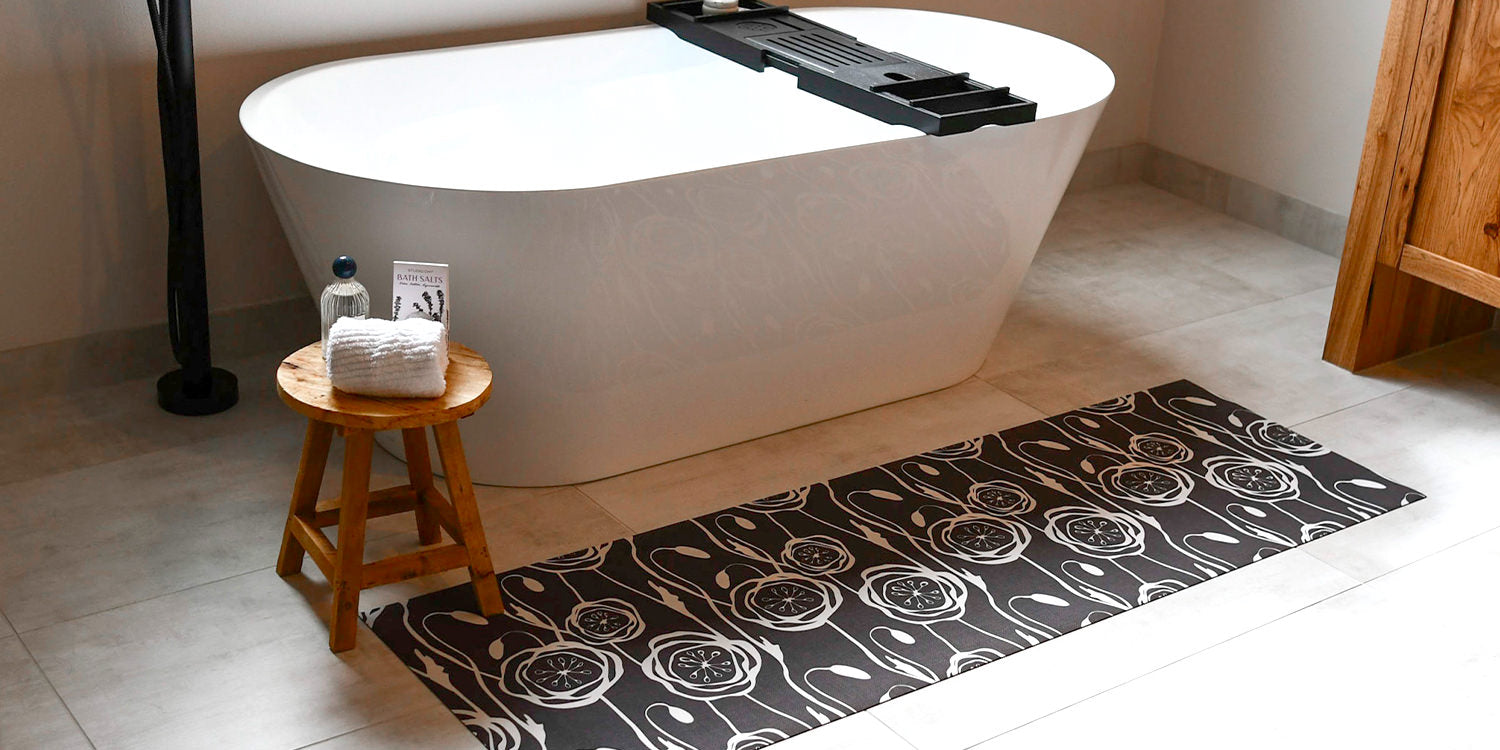 Low-profile Un-Rug decorative bath mat in a stylish and modern floral pattern placed in front of a bath tub to help provide traction.