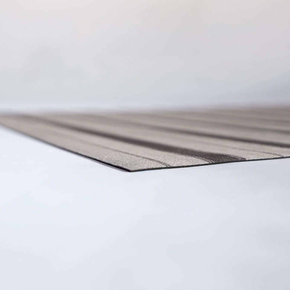 corner of very thin, flat mat with rubber backing and striped fabric surface