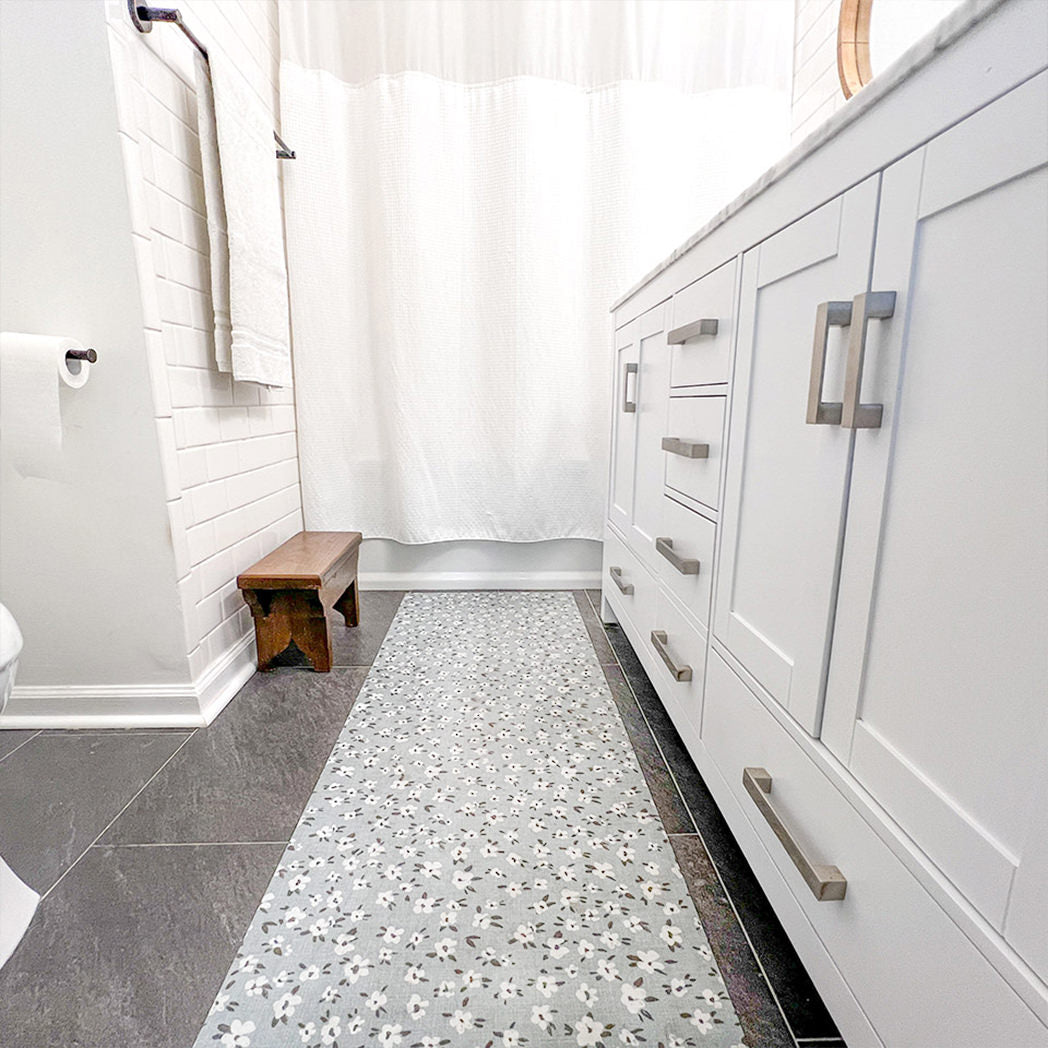 Machine washable Un-Rug bathroom runner in a floral pattern shown in a bathroom in front of a double sink vanity