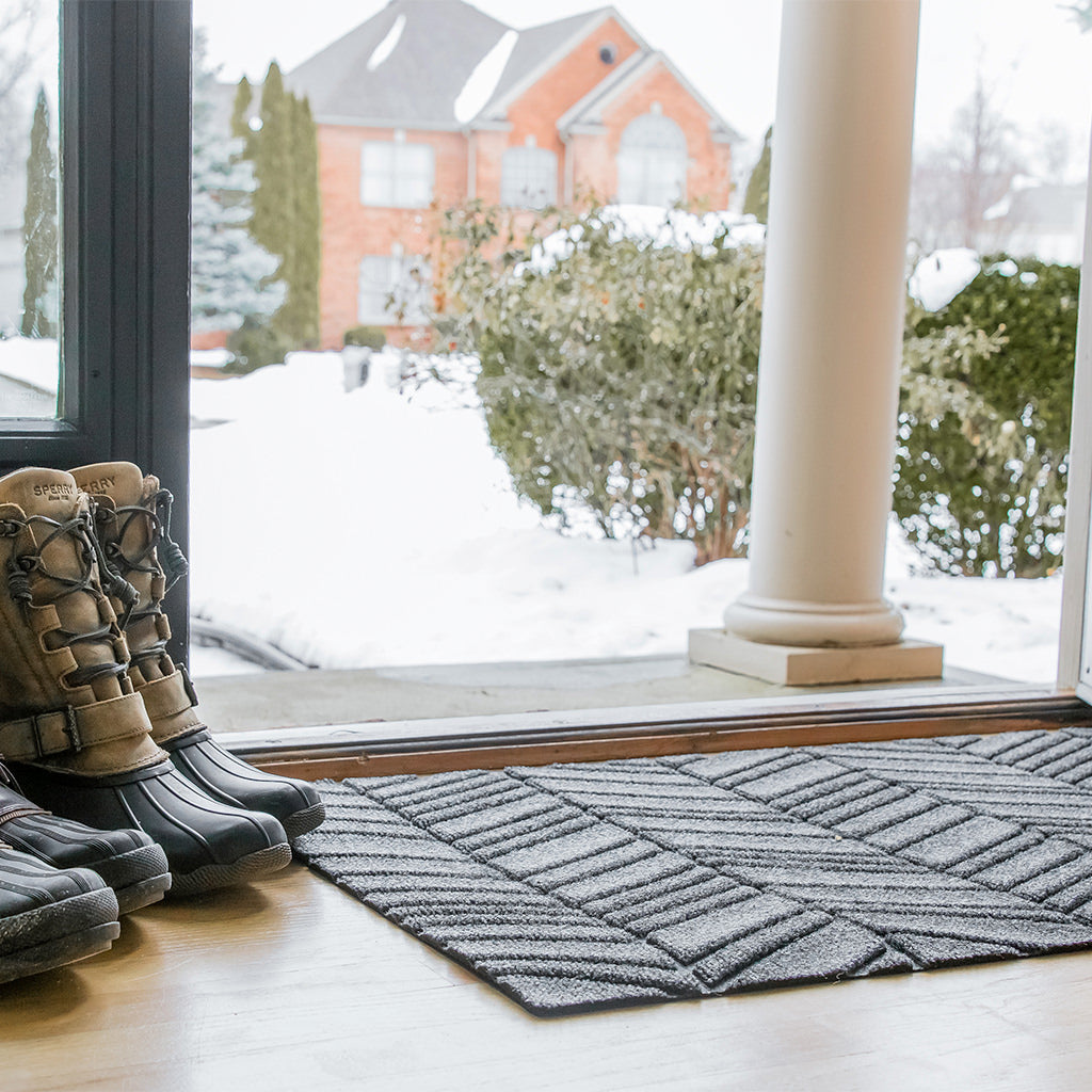 WaterHog Luxe In Vein doormat at the front door with a pair of boots next to it from the snowy winter weather.