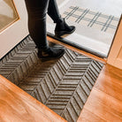 Chevron single door doormat shown in greige on inside of door paired with classic tan black plaid doormat.