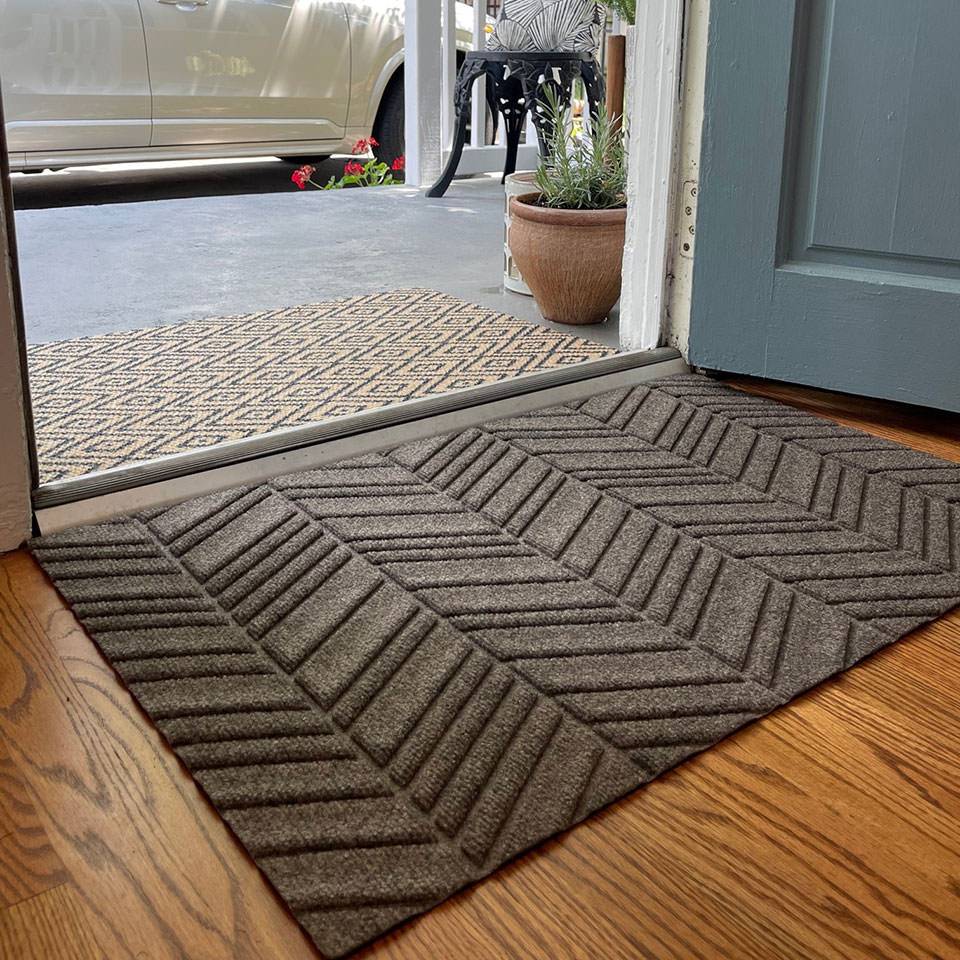 Indoor shot of greige chevron pattern bi level doormat paired with than and black diamond doormat outdoors
