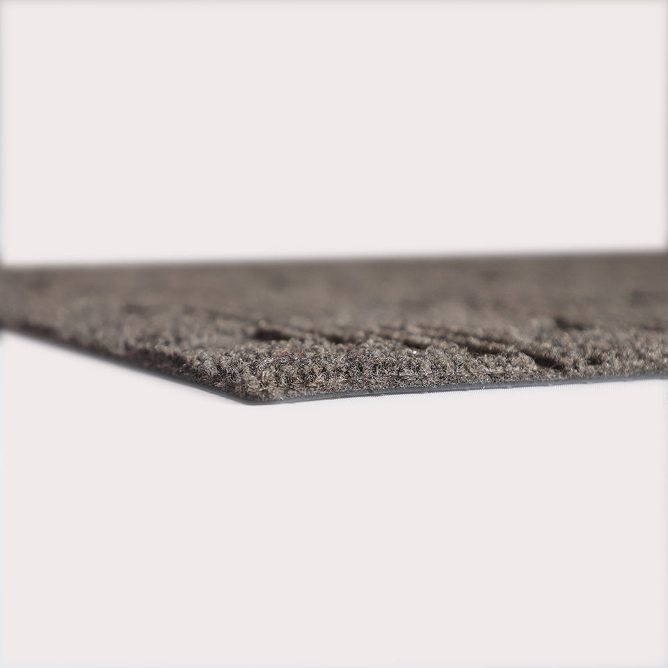 Profile corner image of the Labyrinth doormat in greige, showing the overall 3/8” height and rubber backing.