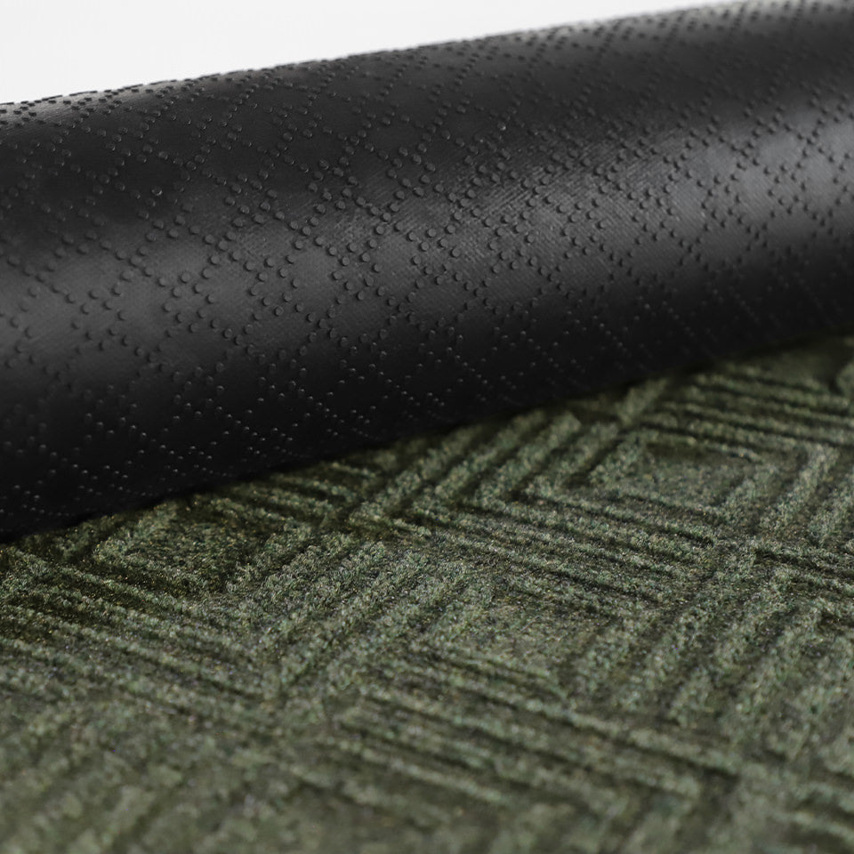 A close-up image of the all-weather Labyrinth mat half rolled showing both the rubber backing and olive surface.