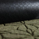 A close-up image of the all-weather Magnolia mat half rolled showing both the rubber backing and olive surface.