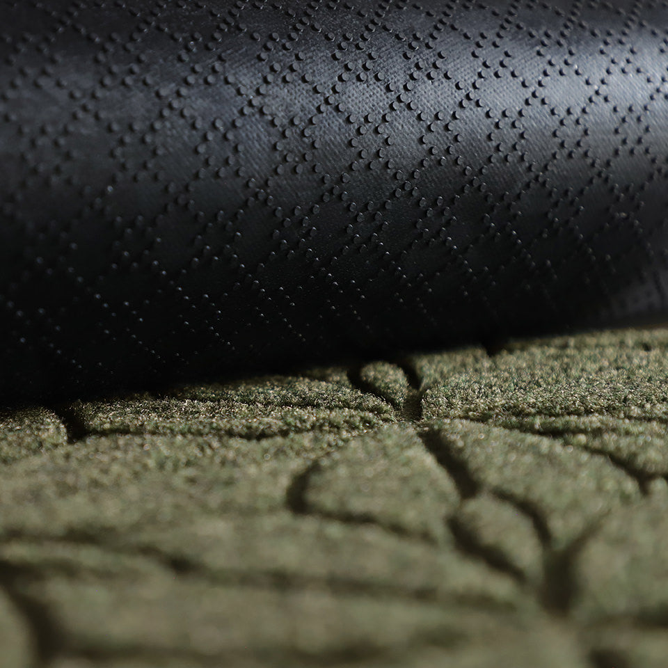A close-up image of the all-weather Magnolia mat half rolled showing both the rubber backing and olive surface.