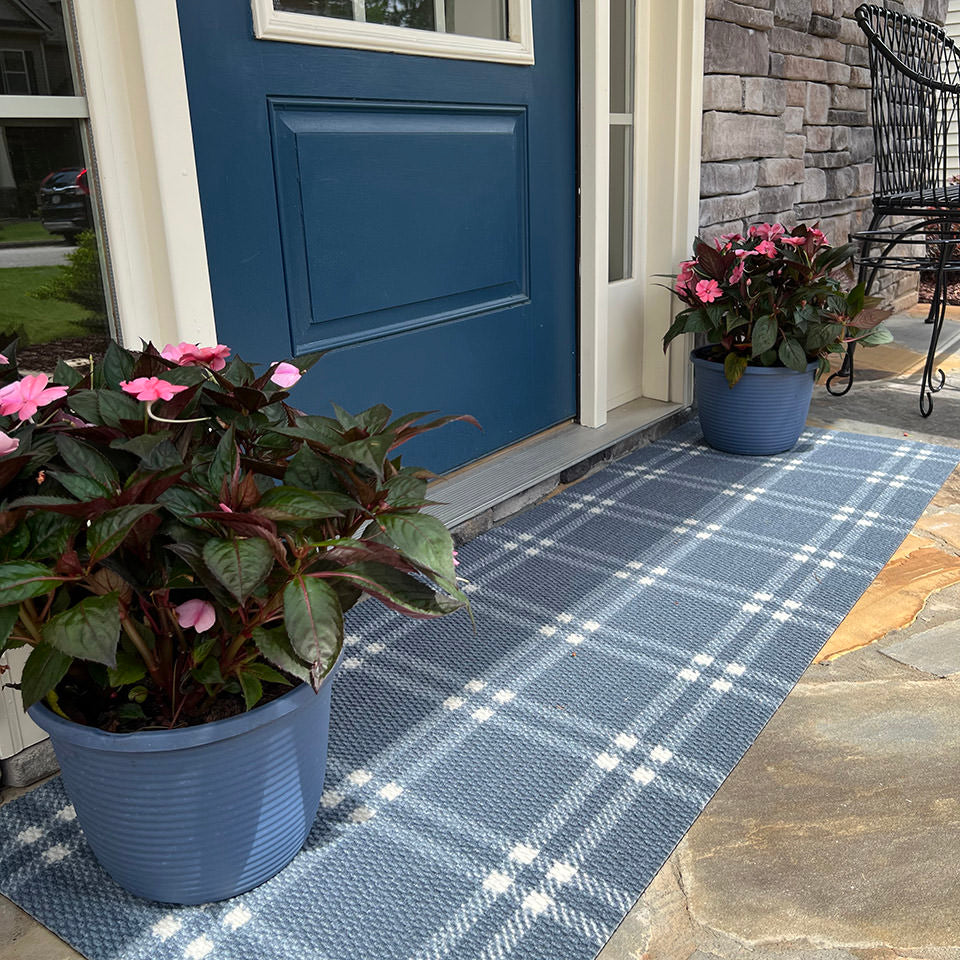 double door grey and white classic plaid doormat in front of blue front door with sidelights