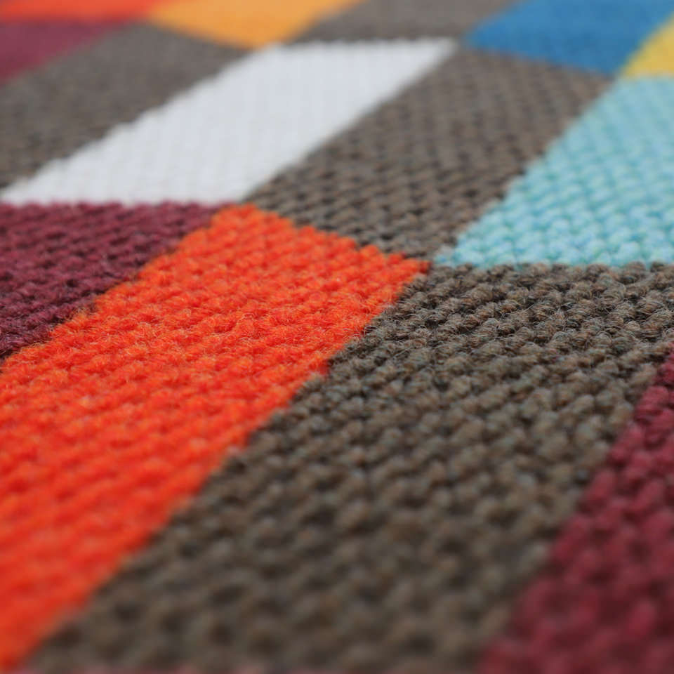 closeup of fabric surface showing colors grey, red, blue, white, and berry