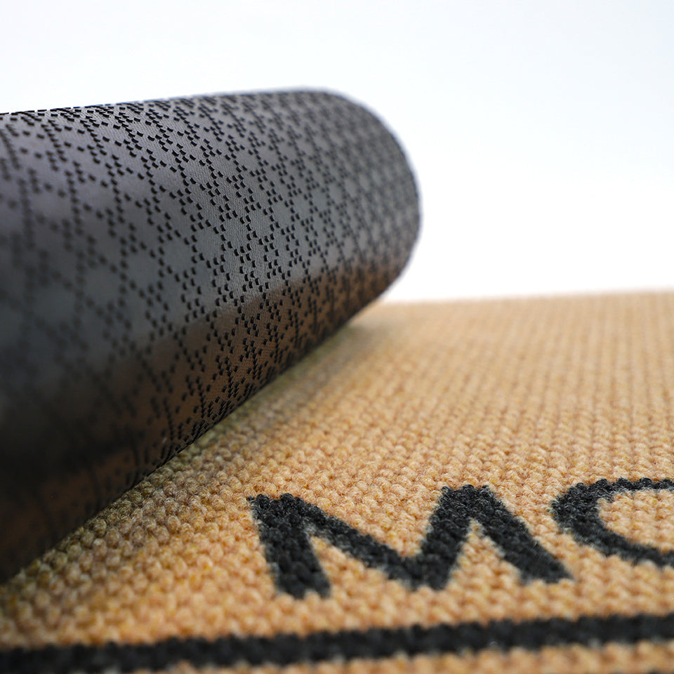 Close up of rubber backing on personalized tan and black doormat customized with last name