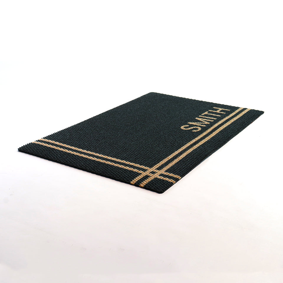 Angle shot of black and tan personalized doormat customized with last name