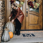 High end brown and black double door size doormat; the Escher Monogrammed doormat is placed outside a double door entryway and will not shed like typical coco mats.