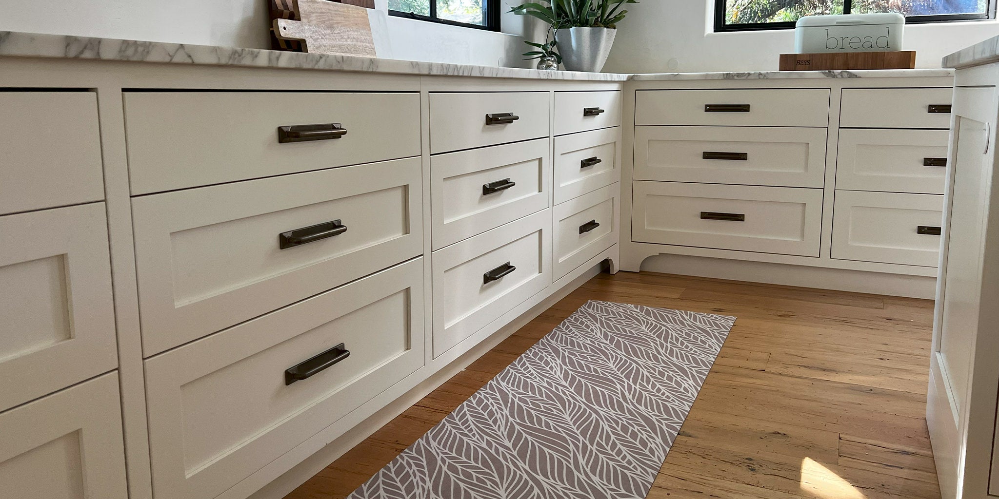 Thin Un-Rug kitchen mat runner is placed at the base of long kitchen counters to protect natural wood floors.