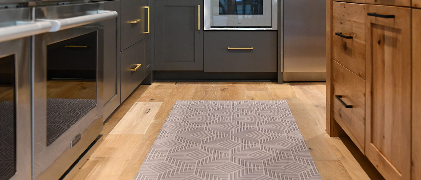 Decorative Un-Rug kitchen mat runner is placed in front of a kitchen sink to protect floors from spills and water.