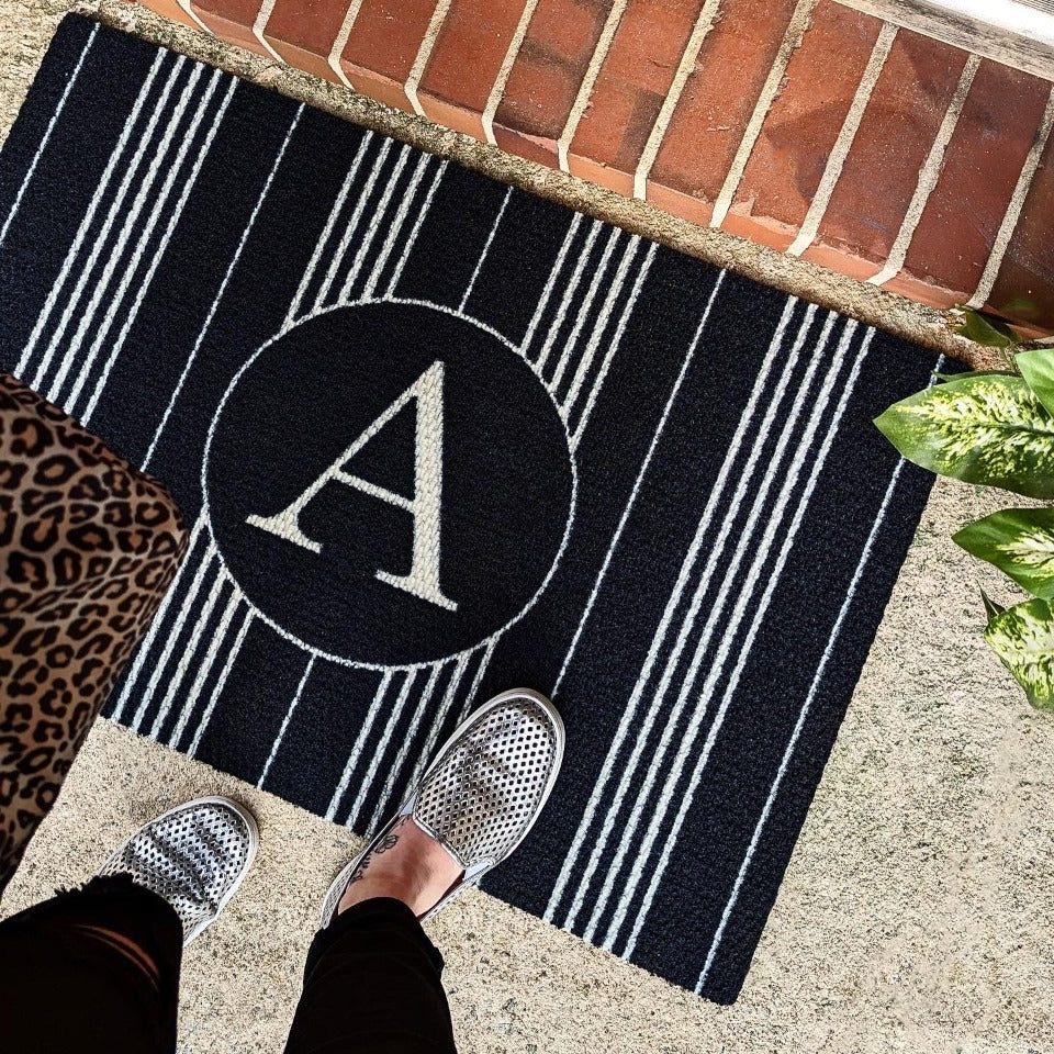 Chic Neighburly monogrammed doormat in black and white stripes placed just outside the front door.