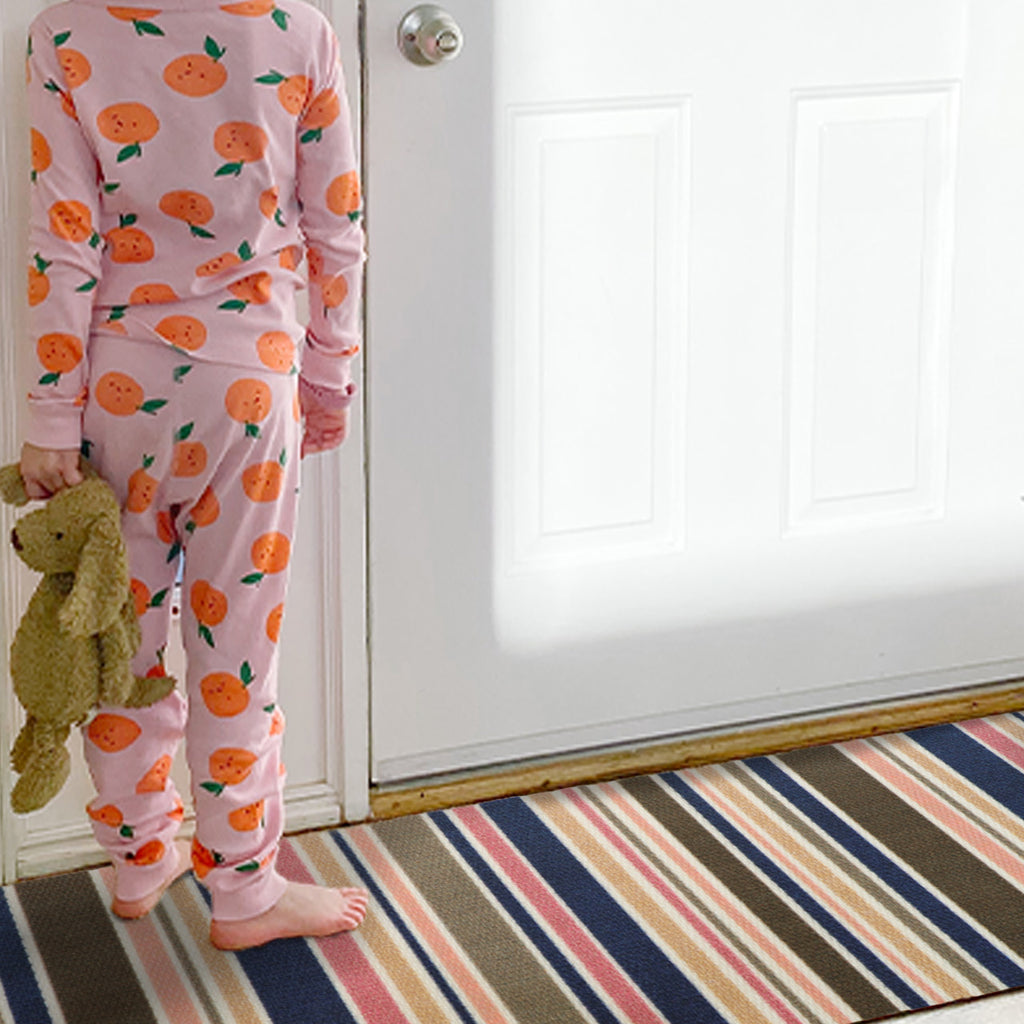 Little girl standing on an entrance mat at the front door.