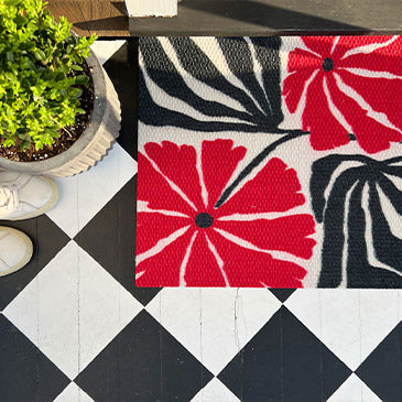 Neighburly's Funk Botanical indoor entrance mat in black, white, and red on a black and while checkered floor to protection and fun design.