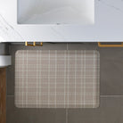 Overhead view of a small Beaded Plaid Happy Feet comfort mat in a bathroom for comfort from the hard, cold grey floors