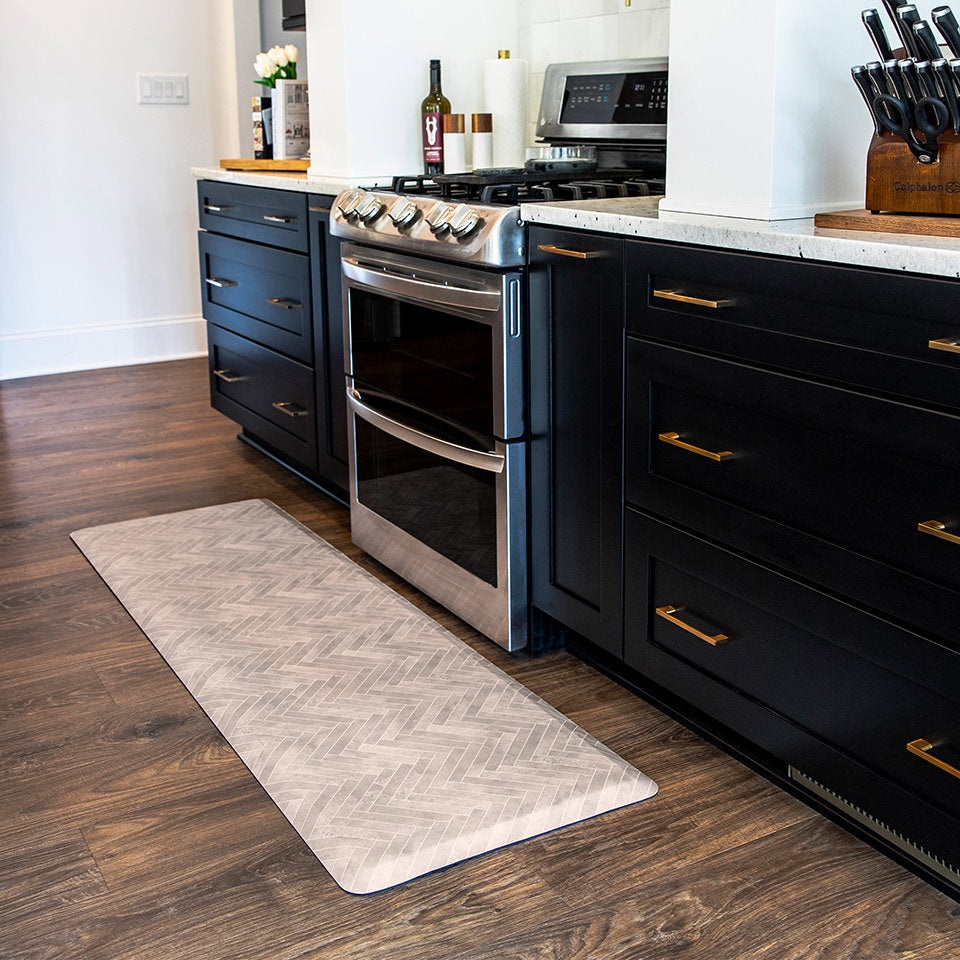 A traditional Herringbone pattern in warm tones featured on a Happy Feet anti-fatigue runner in front of a stove