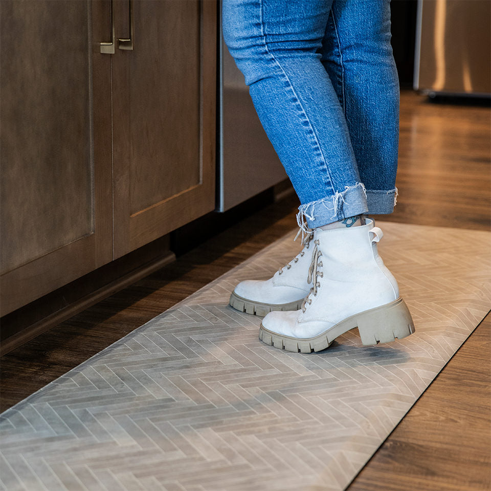 Woman standing a Herringbone Happy Feet runner in a kitchen for standing comfort.