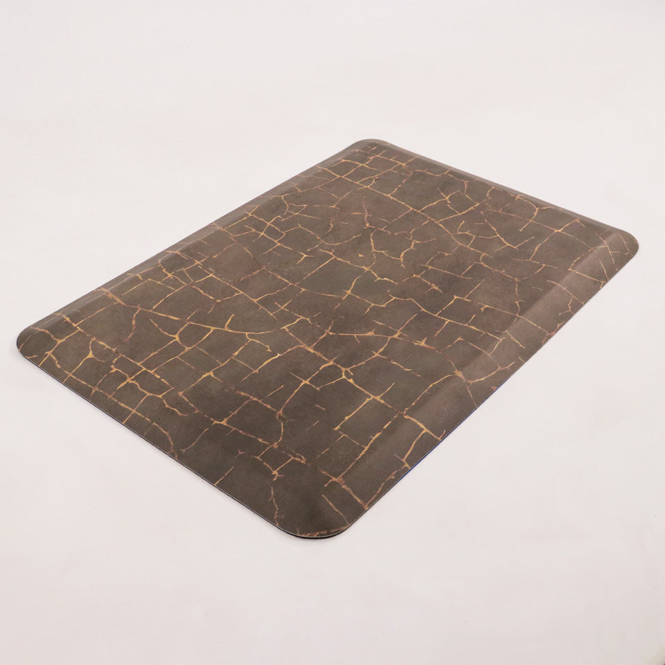 Angled image of anti-fatigue Kintsugi mat, surface of distressed browns and cracks of gold, wipeable and comfortable surface