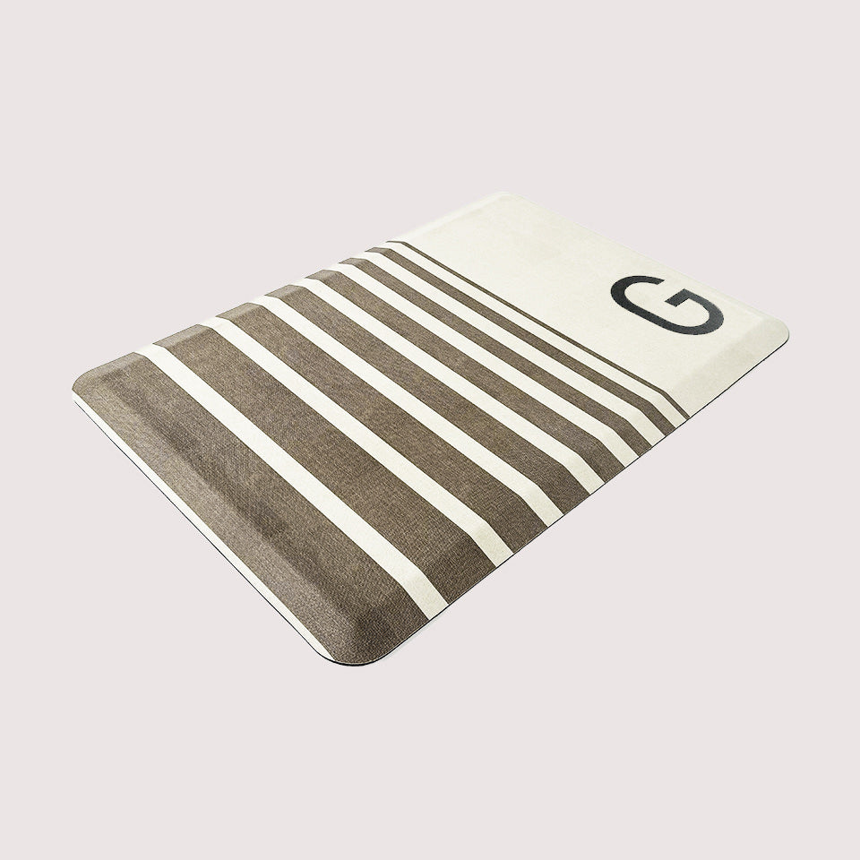 Beautiful canvas-like textured cream colored background with brown stripes and monogrammed letter on an anti-fatigue mat. 