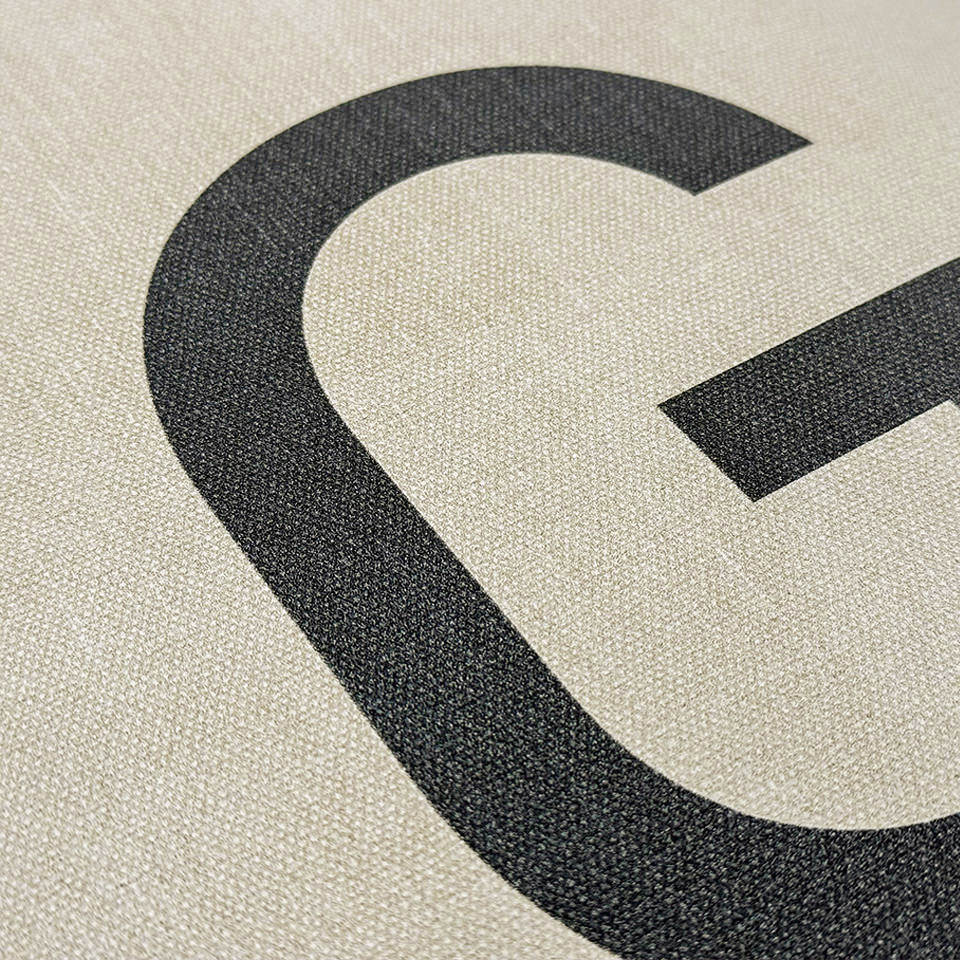 canvas-like textured cream colored mat surface with black monogrammed letter. 